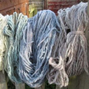 hanks of blue yarn hanging from a fence