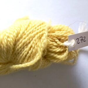 hank of pale yellow sock yarn on a shaded grey to white backgound