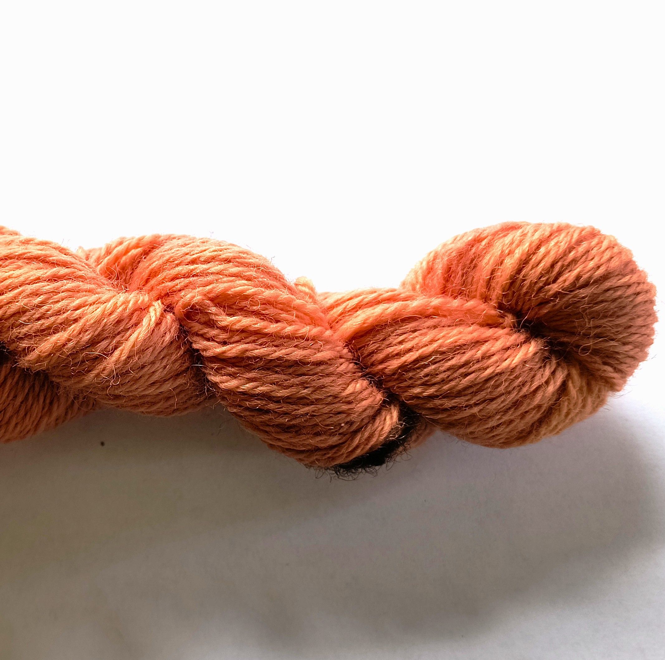 Skein of coral yarn on a white background