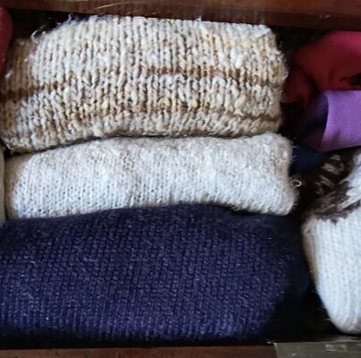 folded woollen jumpers in a drawer