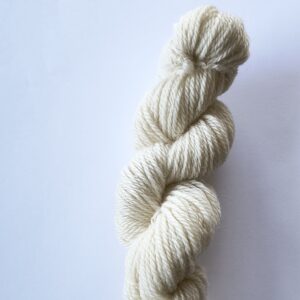 Skein of natural cream undyed wool yarn on a white background