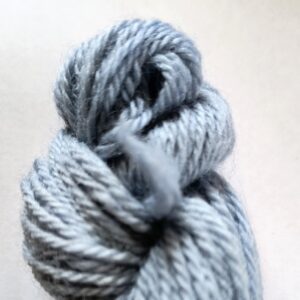End of a sky blue skein of yarn on a white background