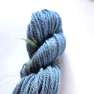 Dark sky blue skein of wool yarn on a white background